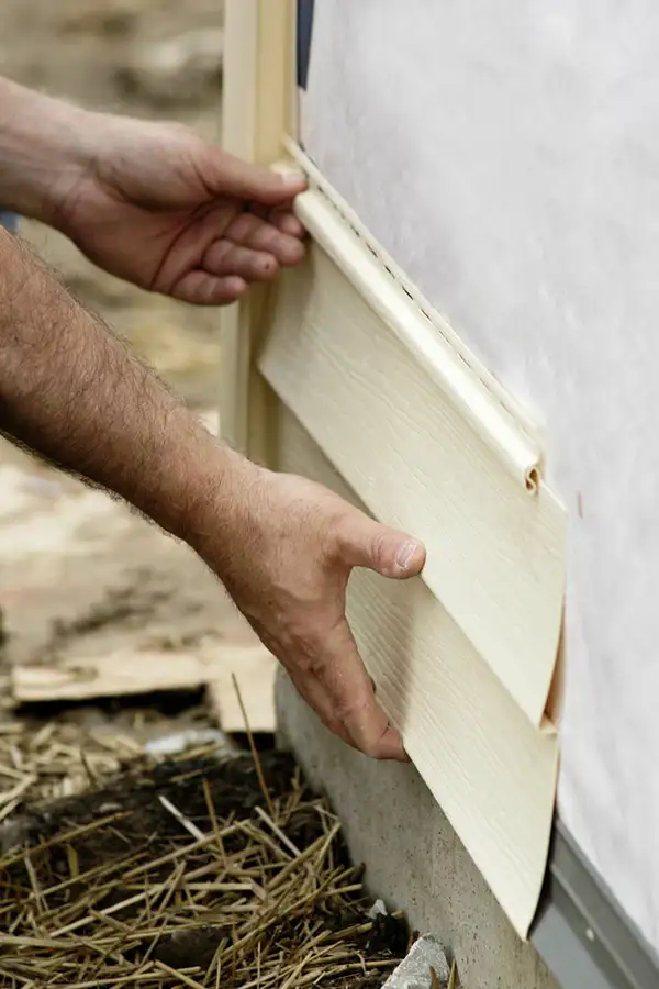 Professional hands repairing damaged vinyl siding - Clinton County, IL